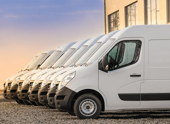 Several white commercial vans parked in a row