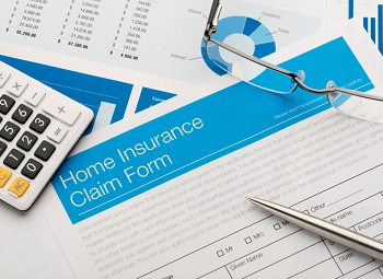 Home insurance claim form with a caculator, glasses and pen laid on top