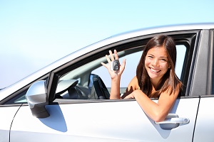 girl leaning outside car window holding up car keys smiling at camera